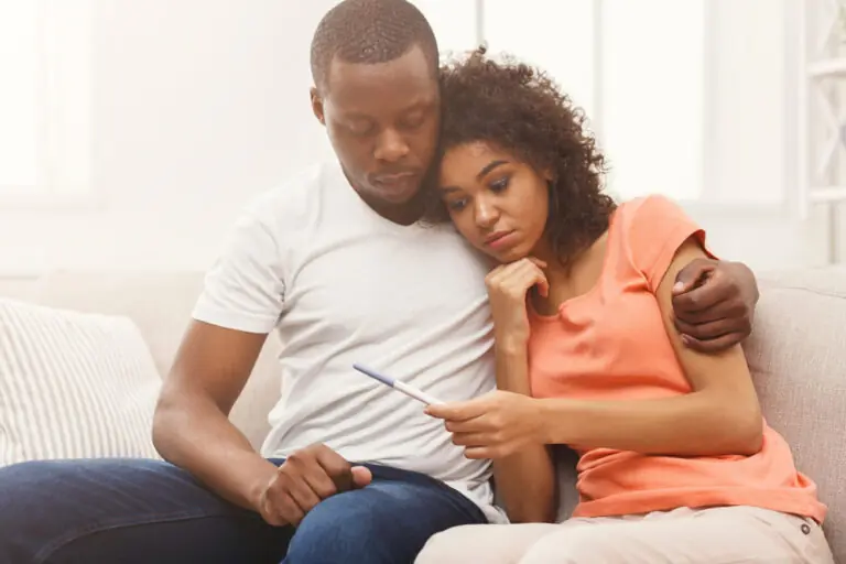 A young couple looks with concern at a pregnancy test as they are on a journey of trying to conceive