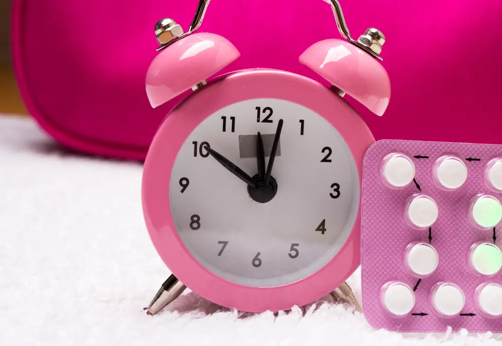 An image of a pink clock with a pack of birth control pills suggesting the idea of stopping birth control when trying to get pregnant